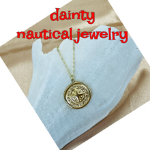 Load image into Gallery viewer, Gold nautical pendant necklace on a white cloth with 'dainty nautical jewelry' text.