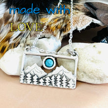 Load image into Gallery viewer, Necklace with mountain and turquoise stone pendant on pebbles and feathers, with 'made with LOVE' text.