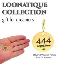 Load image into Gallery viewer, Gold pendant with '444 Angels Near' text held in a hand, branded as Loonatique Collection.