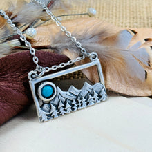 Load image into Gallery viewer, Necklace with a mountain and turquoise stone pendant on a natural background