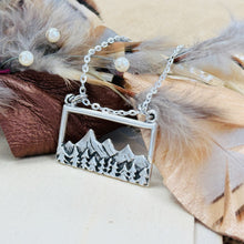 Load image into Gallery viewer, Silver mountain pendant necklace on a neutral background with feathers