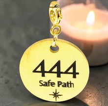Load image into Gallery viewer, Gold pendant with '444 Safe Path' engraving in front of a candle