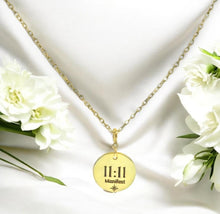 Load image into Gallery viewer, Gold necklace with a pendant displaying '11:11 Manifest' on a white background with flowers.