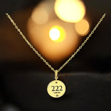 Load image into Gallery viewer, Gold necklace with a round pendant featuring the number 222 on a blurred background.